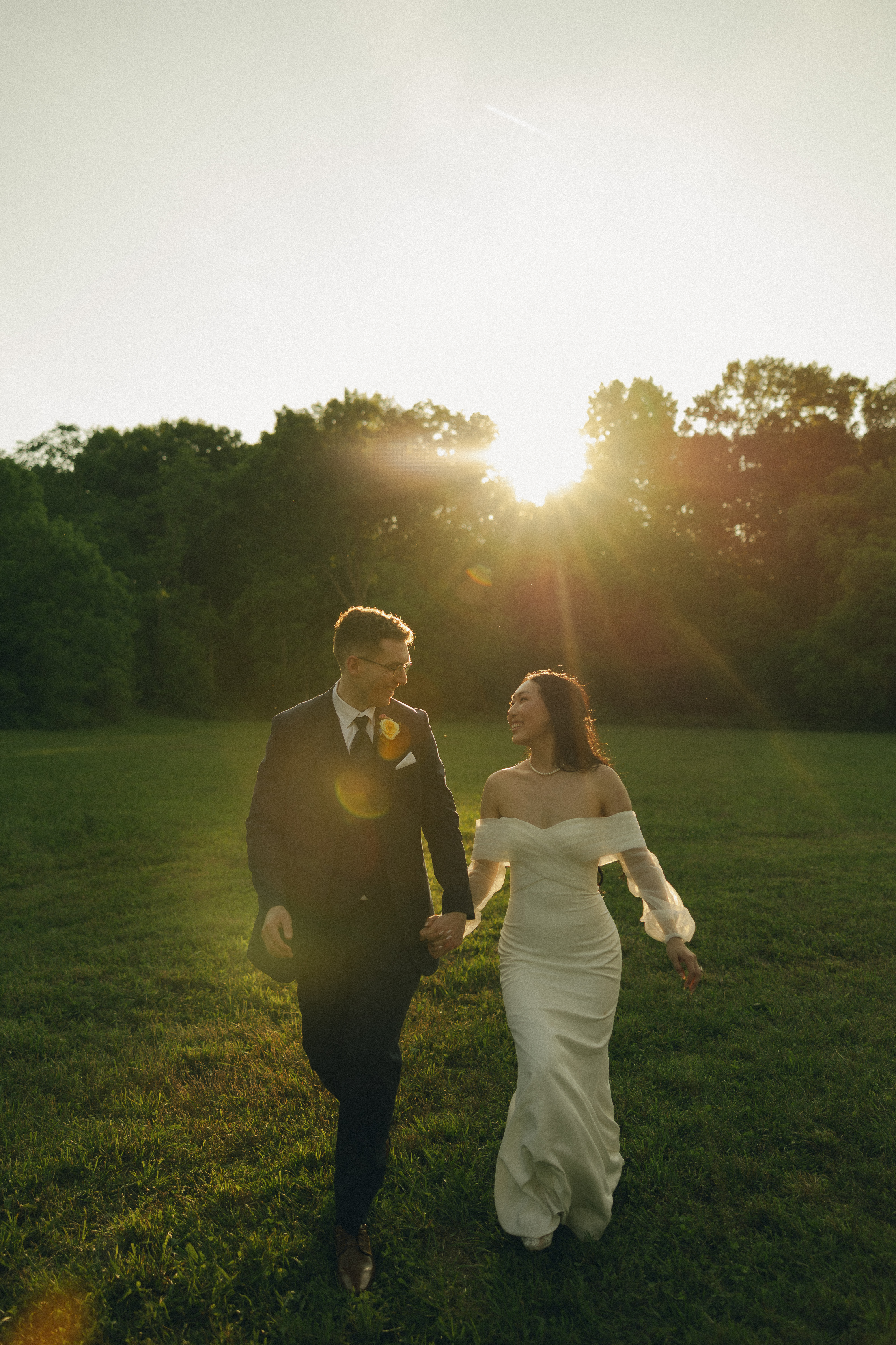 Bride and groom walking hand in hand at golden hour sunset